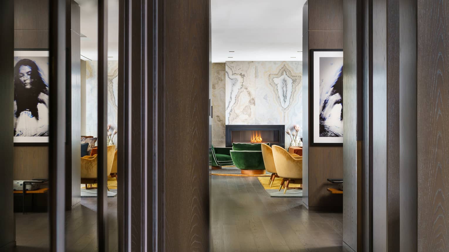 Entryway to suite, dark wood floors, mustard- and emerald green-coloured arm chairs by fireplace
