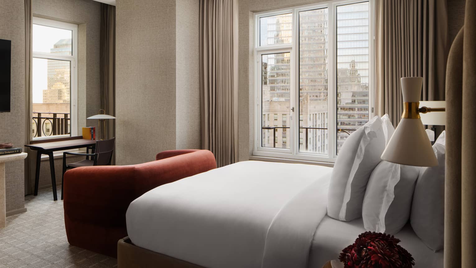 Hotel bedroom with king bed and deep red velvet love seat