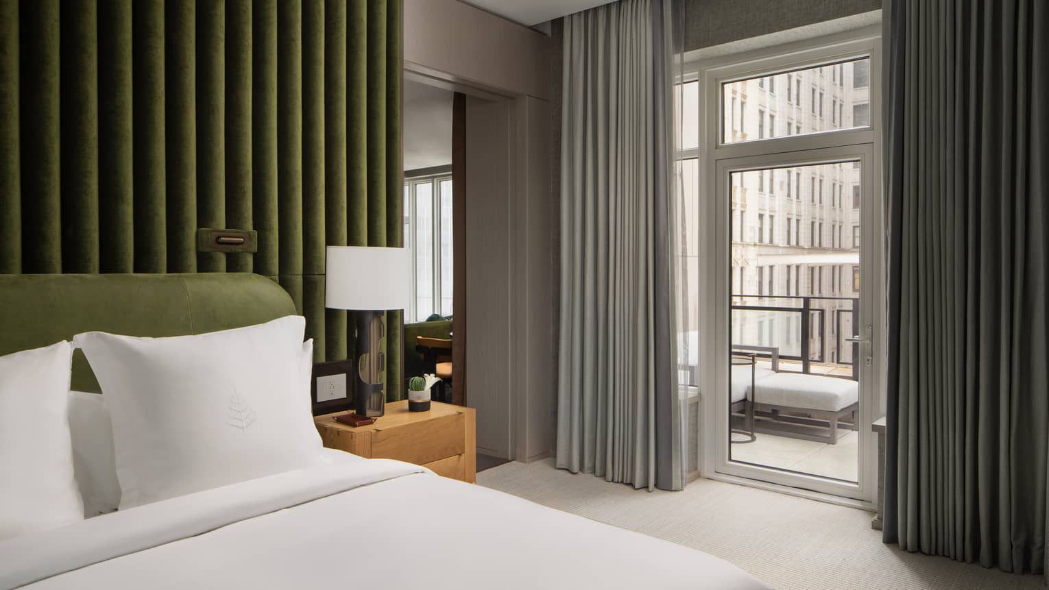 Hotel bedroom with forest-green accent wall, king bed and walk-out city-view terrace