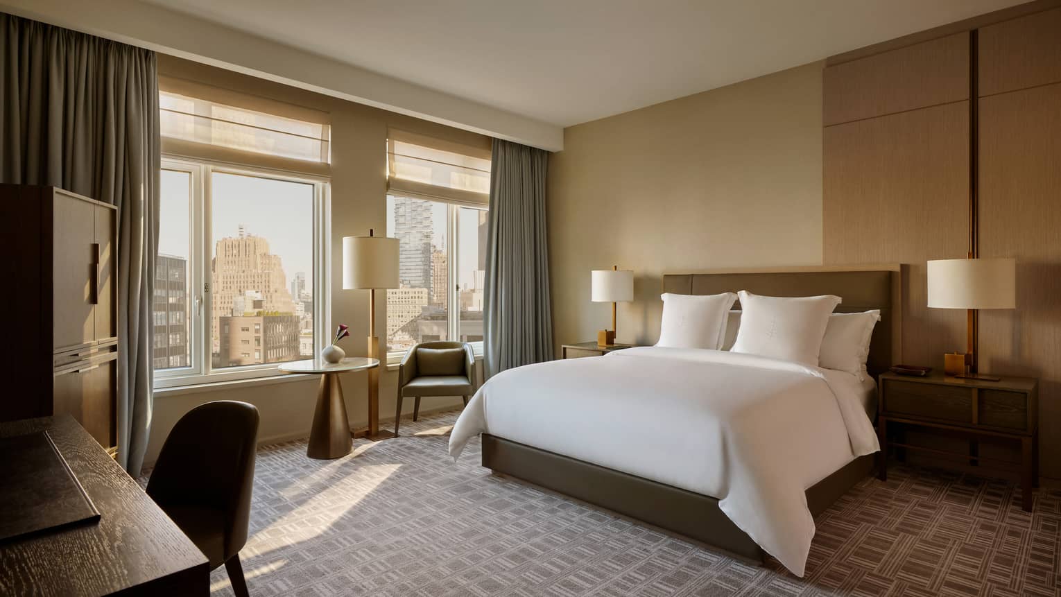 Luxury hotel room with king bed, windows with city view, desk and chair