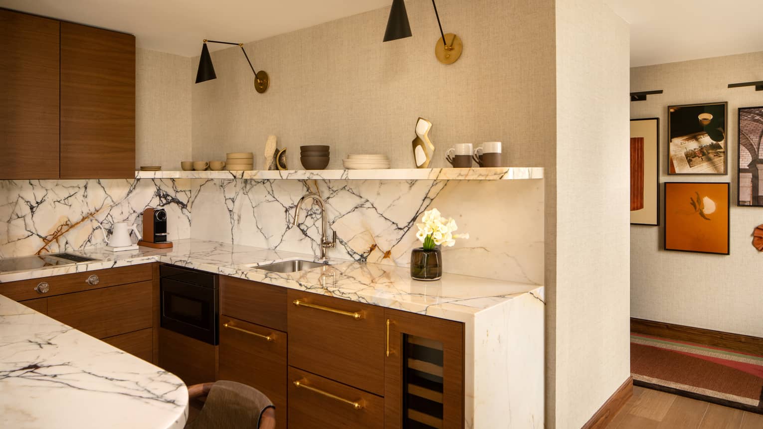 Modern kitchen in a stylish hotel suite, featuring white and black marble counters and backsplash as well as wooden cabinets