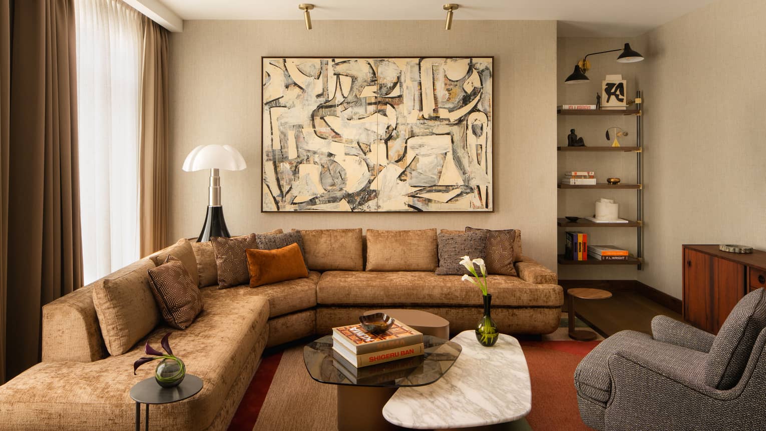 Contemporary living room of a hotel suite, with large sectional sofa, marble coffee table, abstract artwork and arm chair