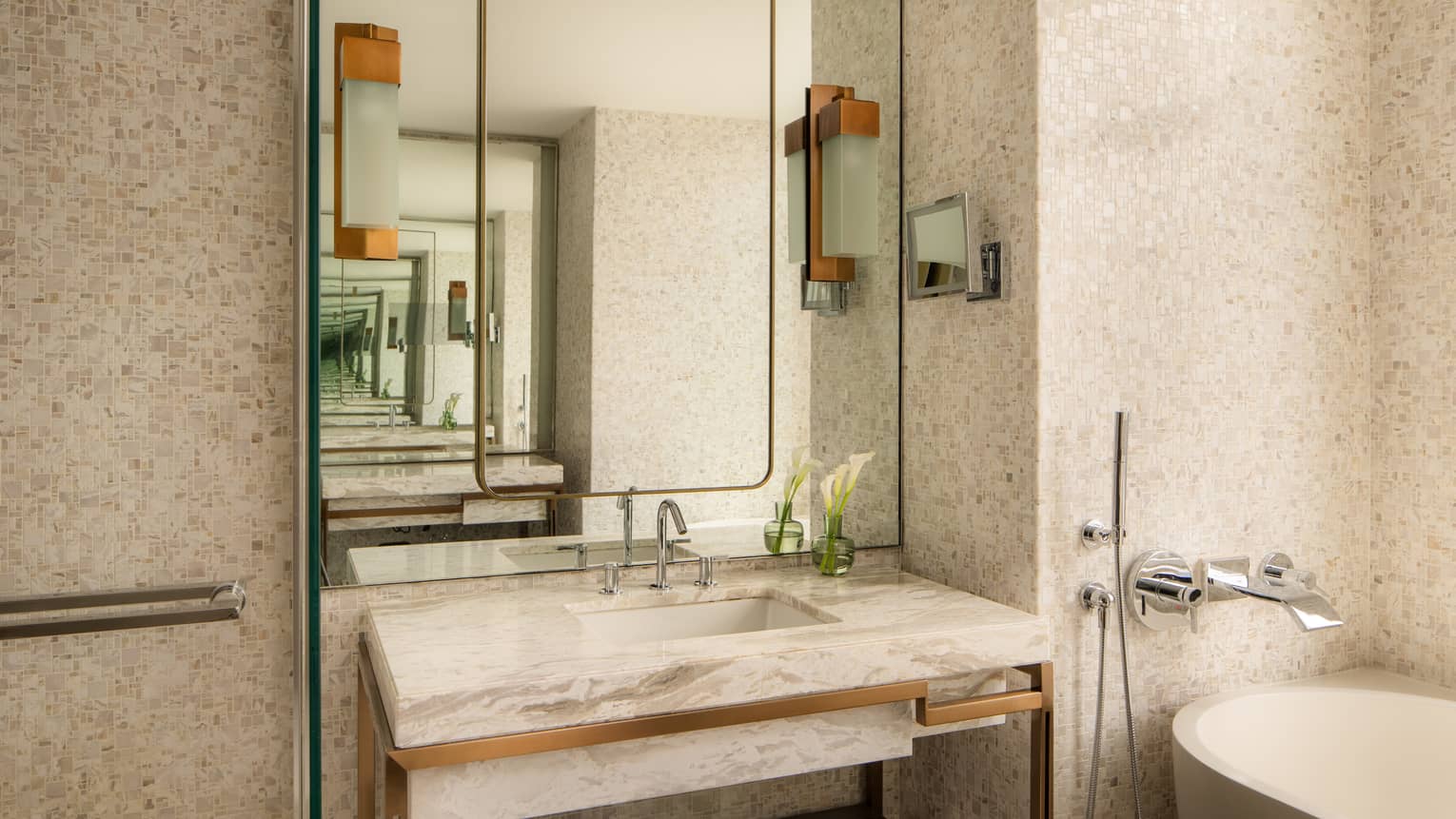 Modern hotel room bathroom featuring a marble vanity and an oval tub