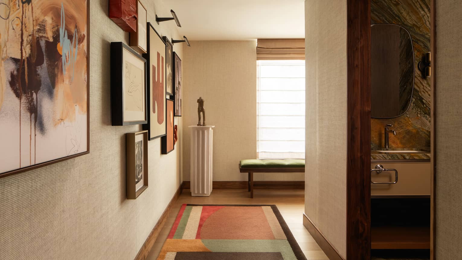 Hallway in a contemporary hotel suite with geometric, colourful rug and framed artwork