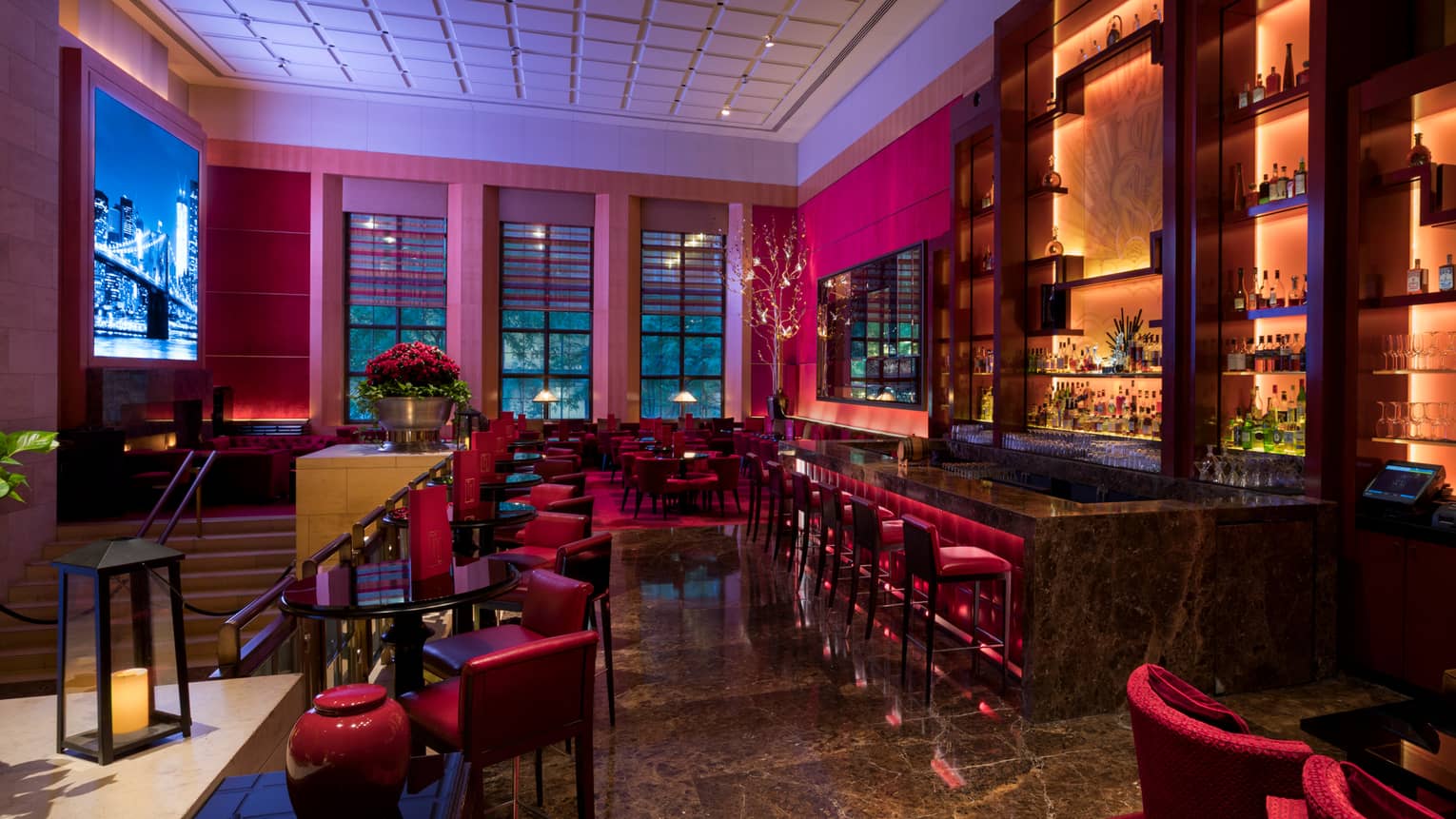 Ty Lounge at dusk with red velvet chairs, stools, lanterns on tables, lights behind bar