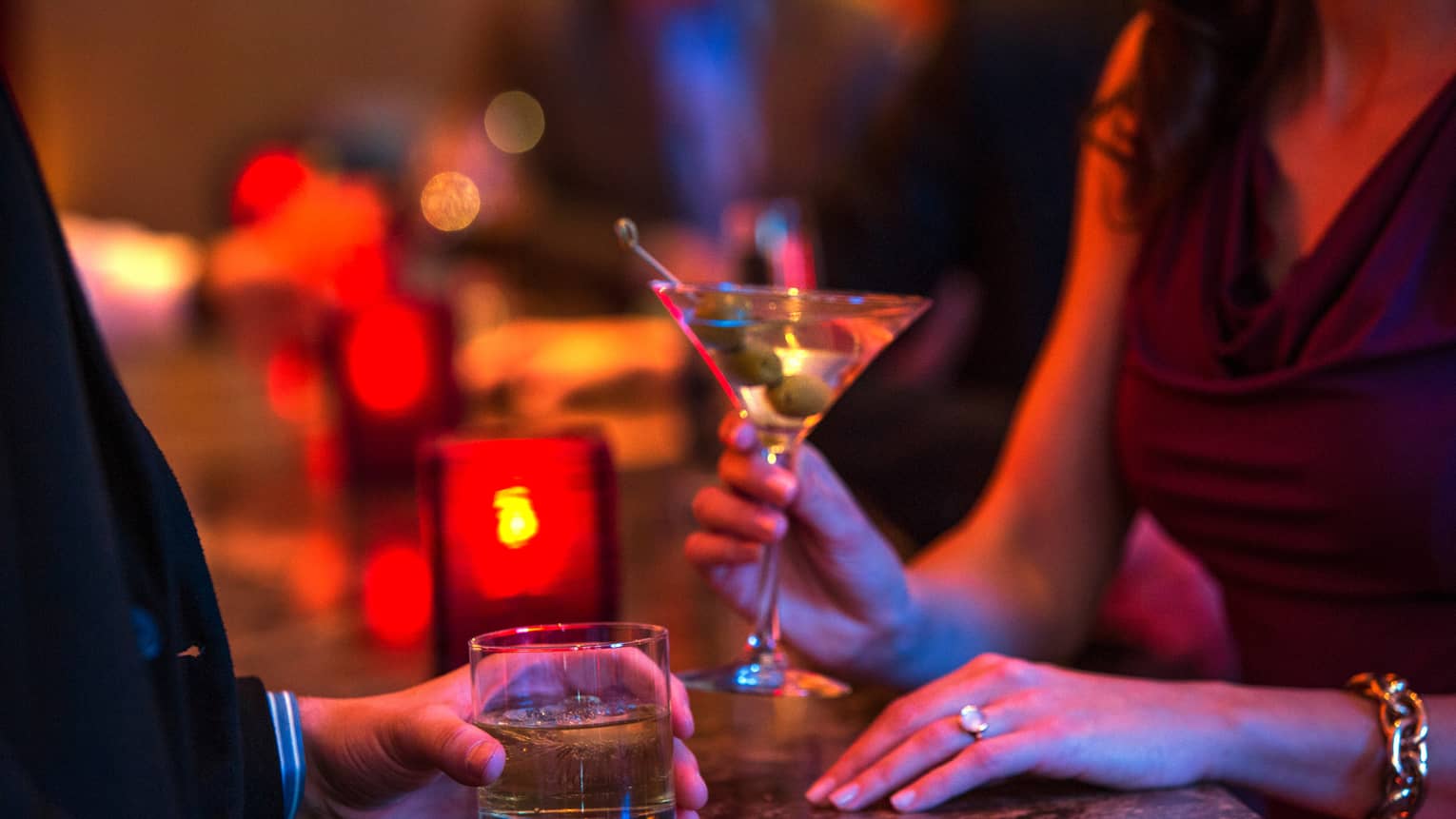 Ty Bar close-up of man and woman holding cocktails in rock and martini glasses, red candle