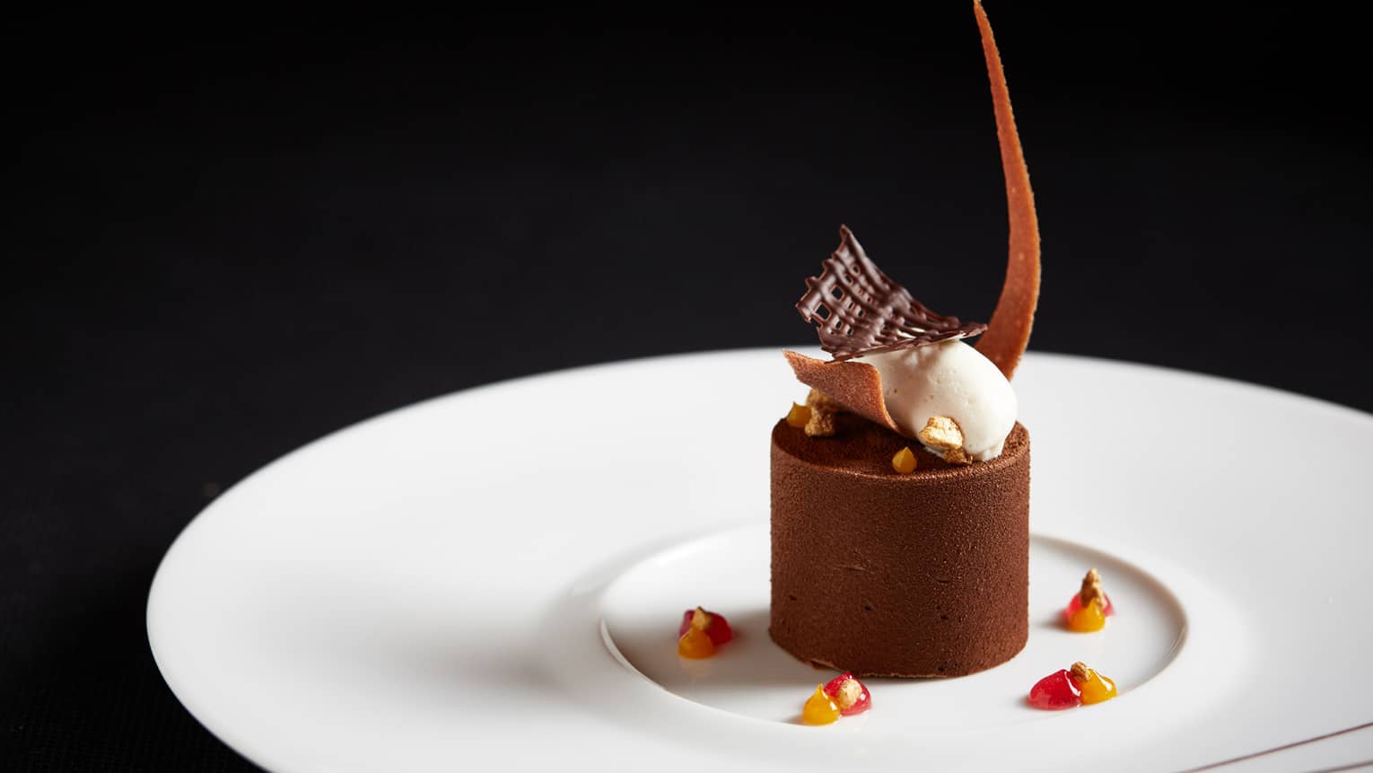 Round chocolate dessert topped with cream and sculpted chocolate garnishes 