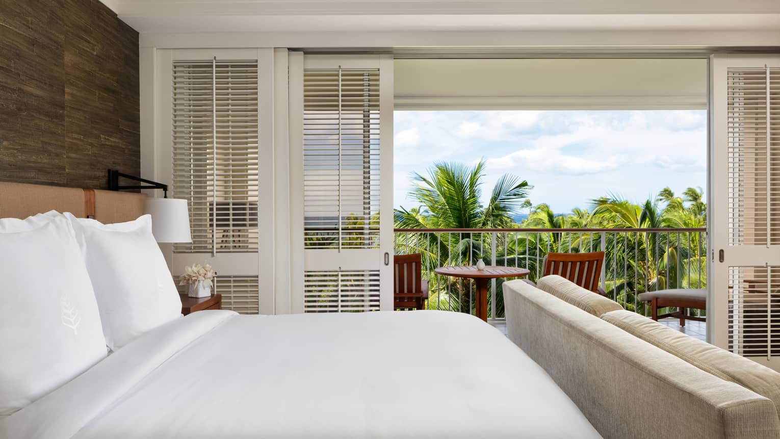 Hotel room with king bed and balcony overlooking palm trees
