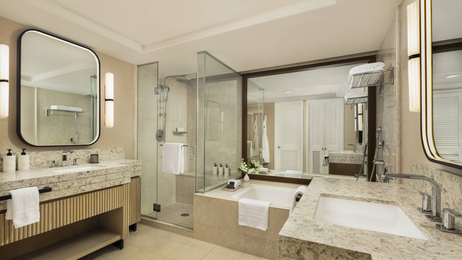 Hotel room bathroom featuring sunken tub, separate glass shower and a sink vanity on each side of the bathroom