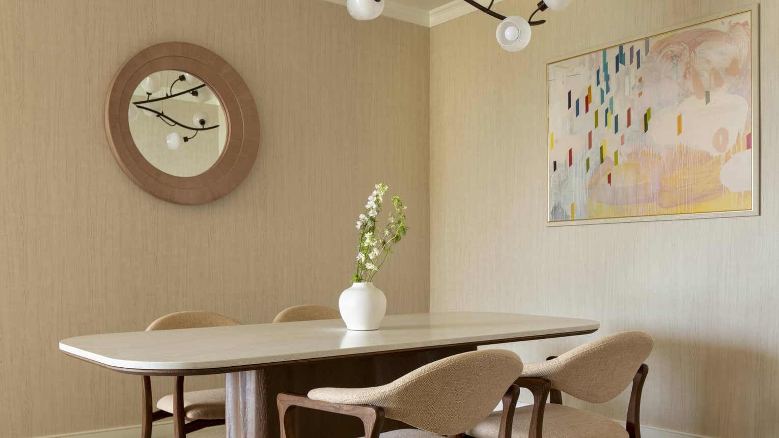 Contemporary dining room featuring a rectangular table with curved corners, four chairs, a mirror, artwork and lighting fixture