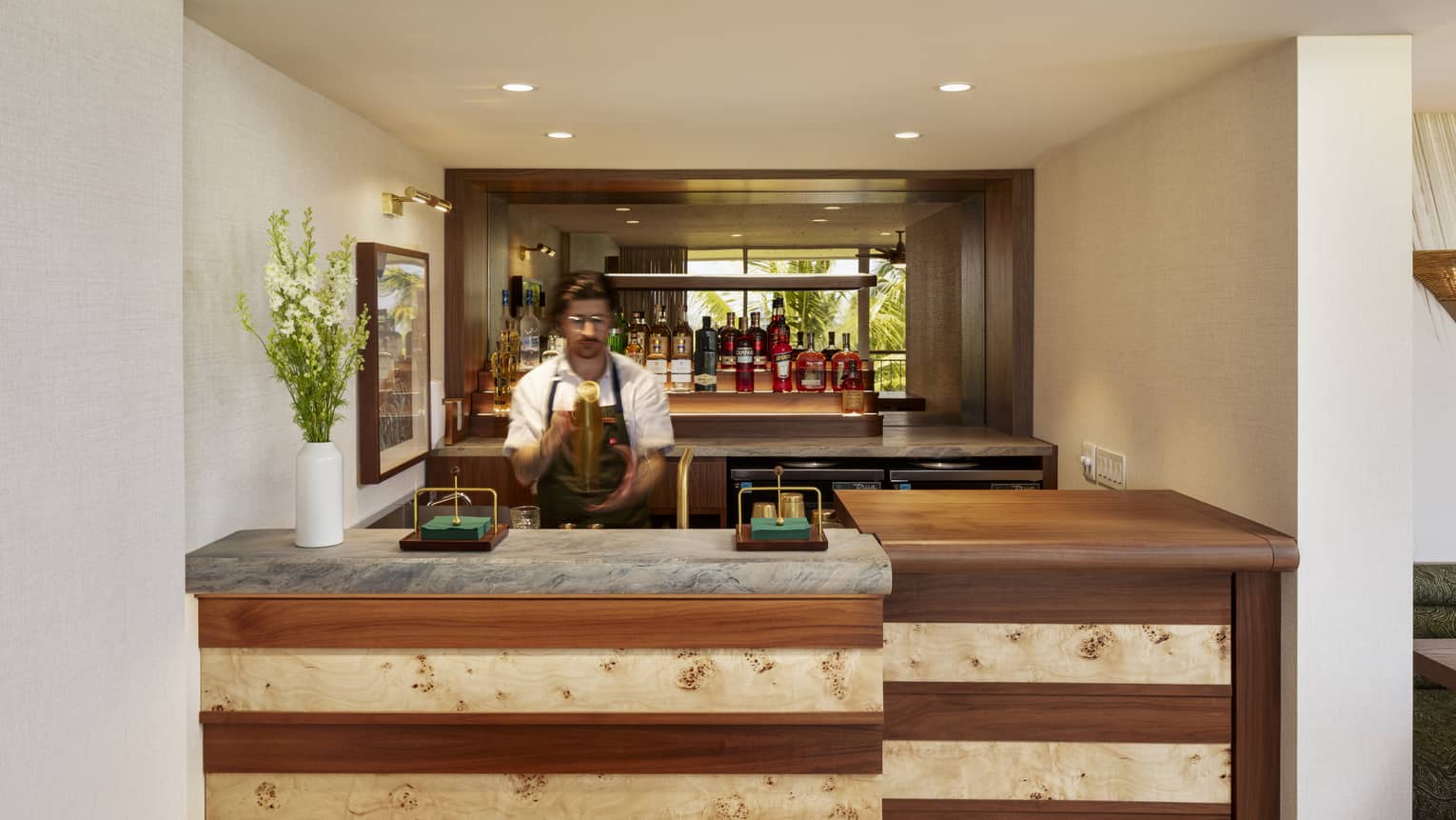 Bartender makes a drink behind a wooden bar counter