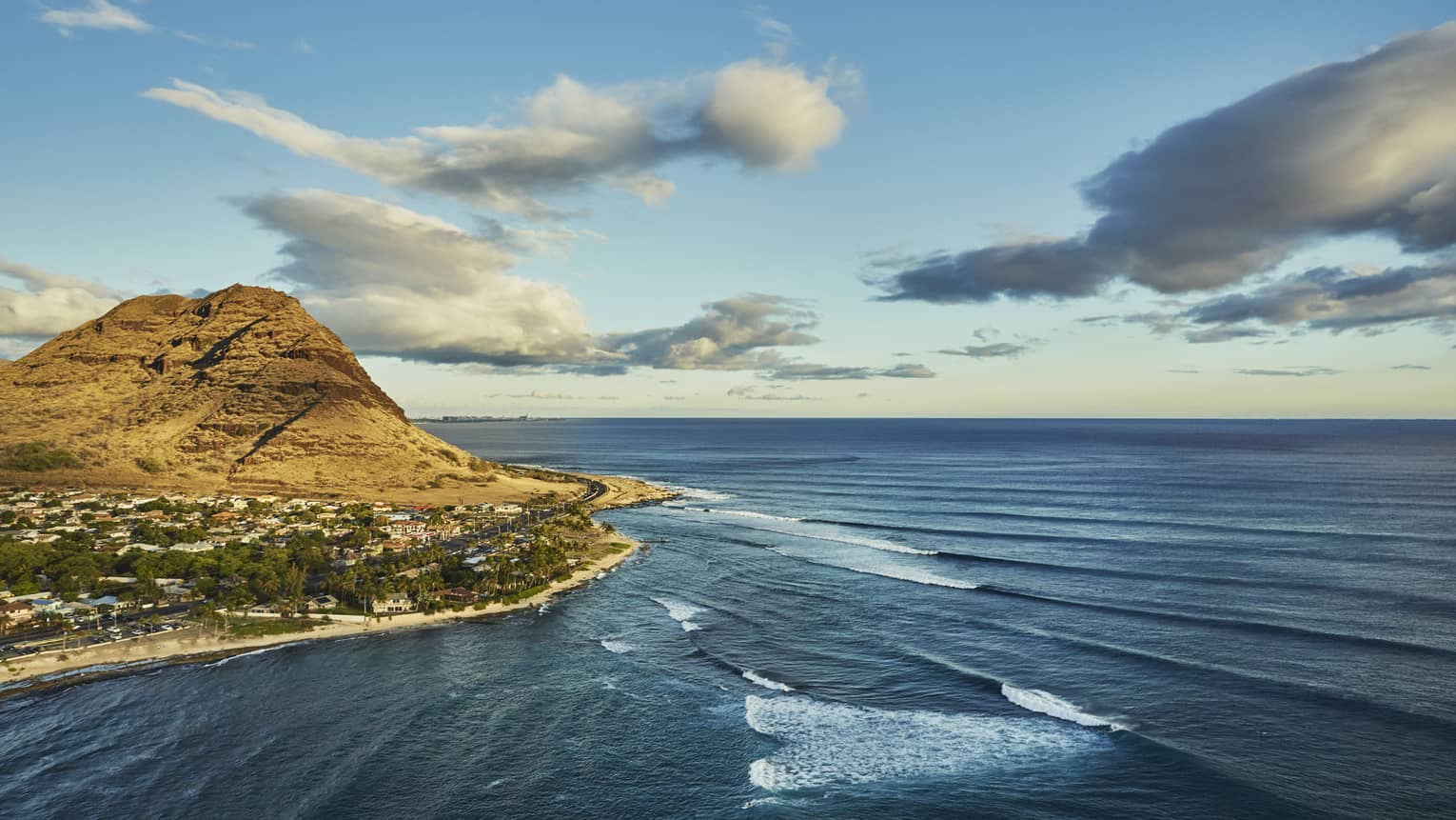 Sweeping view of Oahu, Hawaii mountain, beach and resort surrounded by ocean, waves
