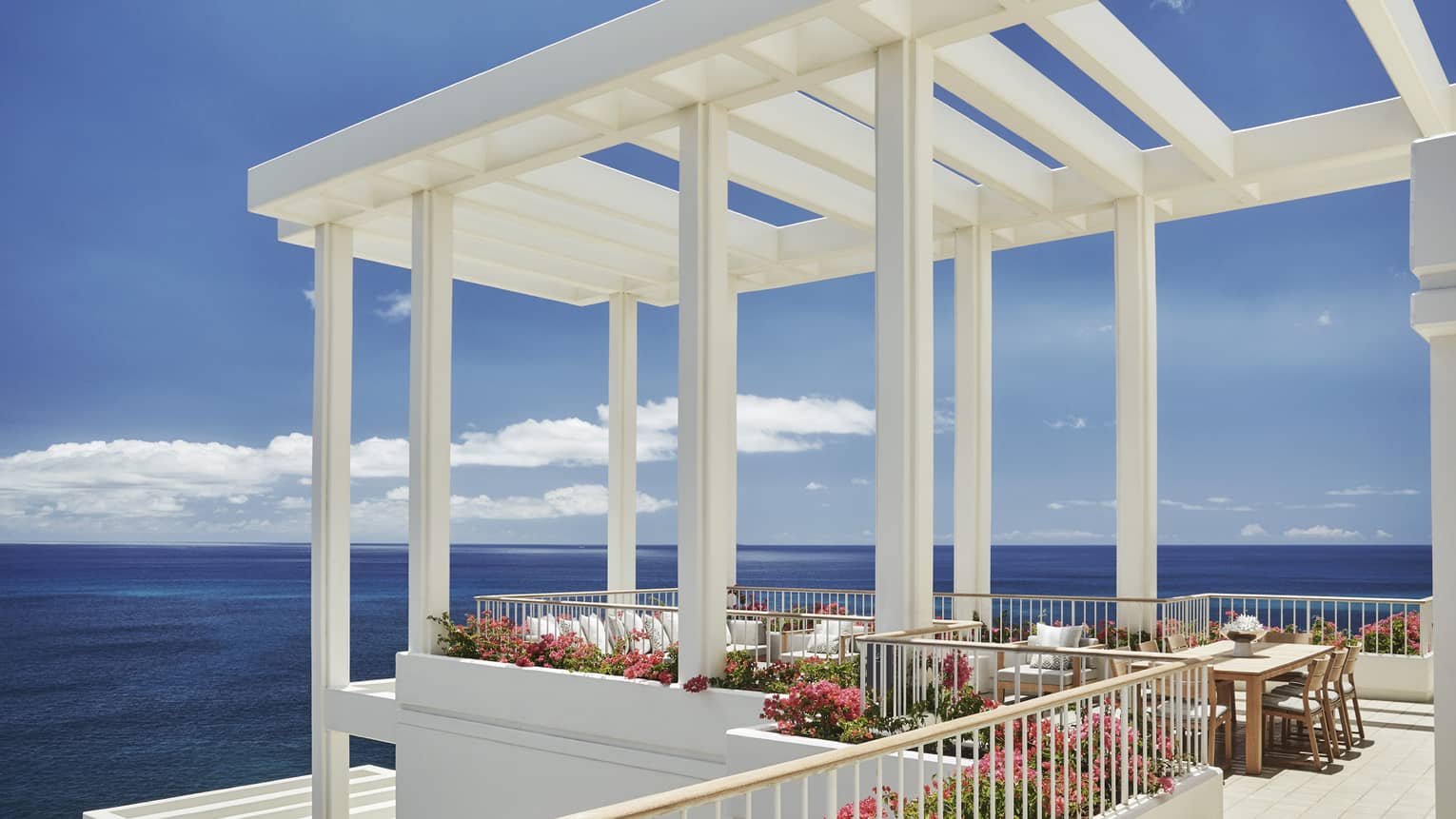 Penthouse Suite patio tables, chairs under white pergola, tropical pink flowers