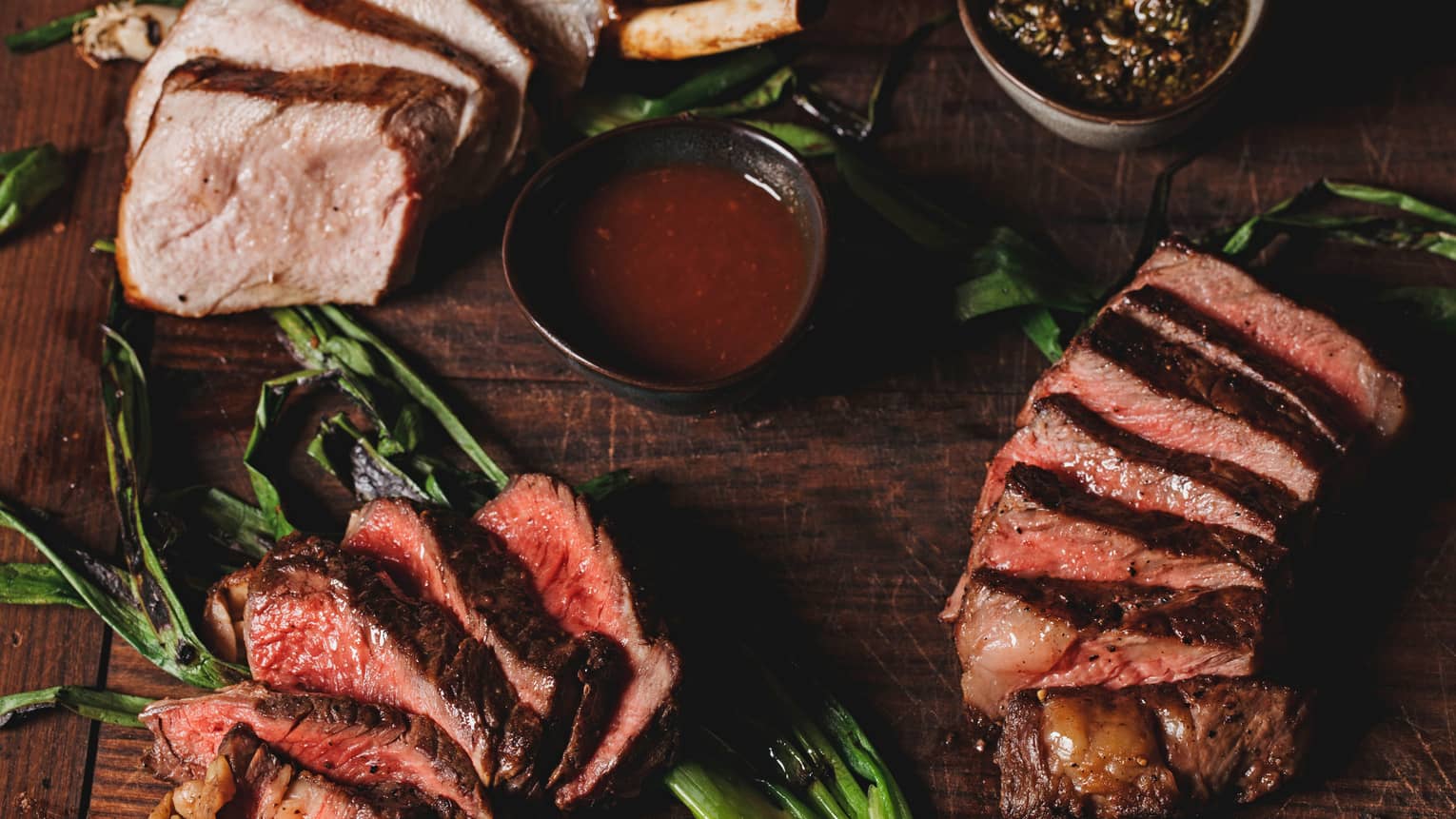 A aerial view of the La Hiki Steak over green onions with a red sauce on the side