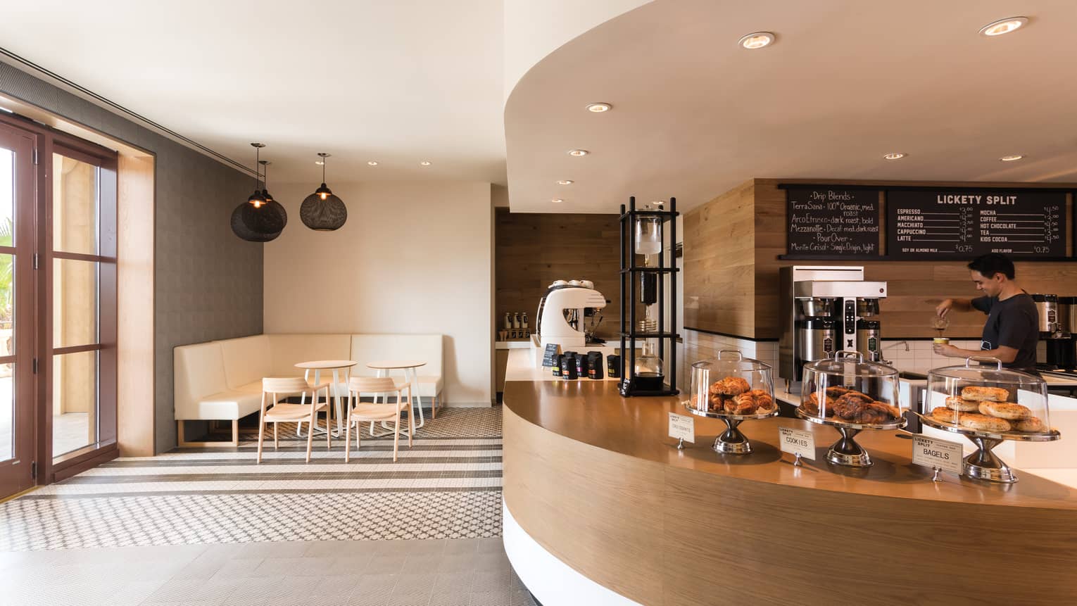 Curved wood desk at Lickety Split bakery with fresh pastries under glass displays, coffee station