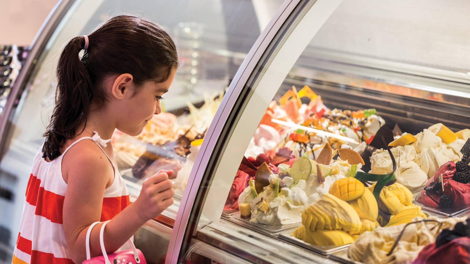 Girl stands at Lickety Split glass counter, looks in at gelato flavours on display