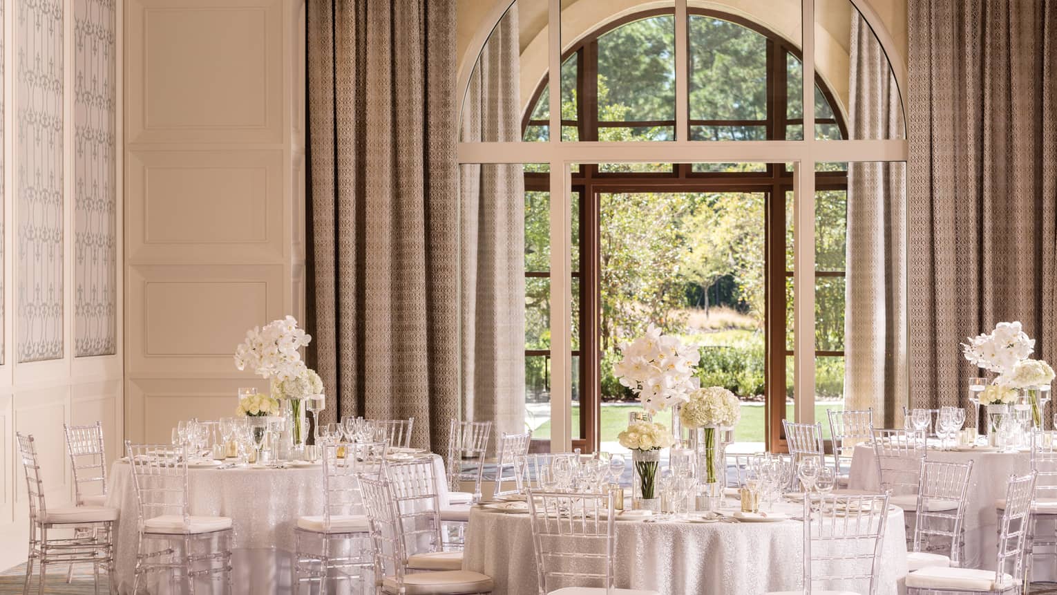 The Palm Ballroom with elegant white banquet tables under large, sunny arched window