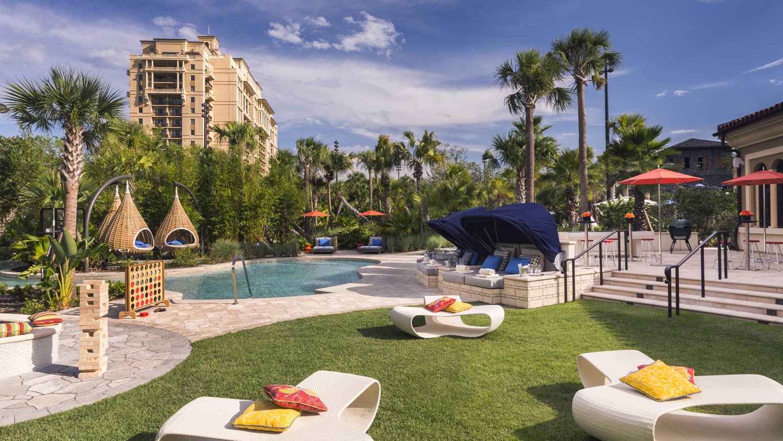 White patio chairs, hanging baskets, palm trees around swimming pool deck