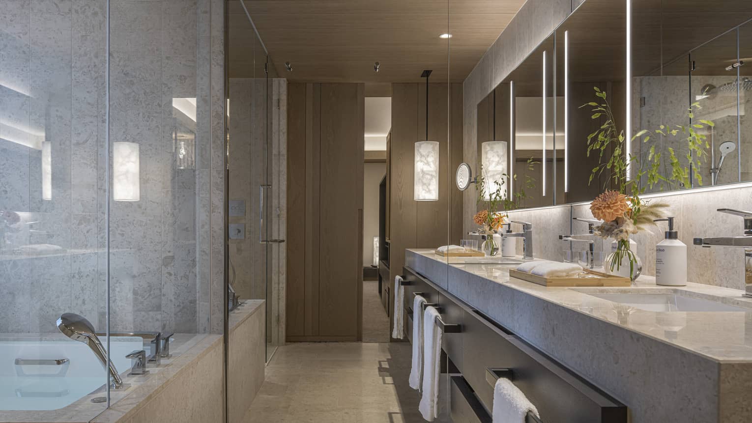 Modern bathroom of hotel suite, with luxury bath tub, long double vanity and long illuminated mirror