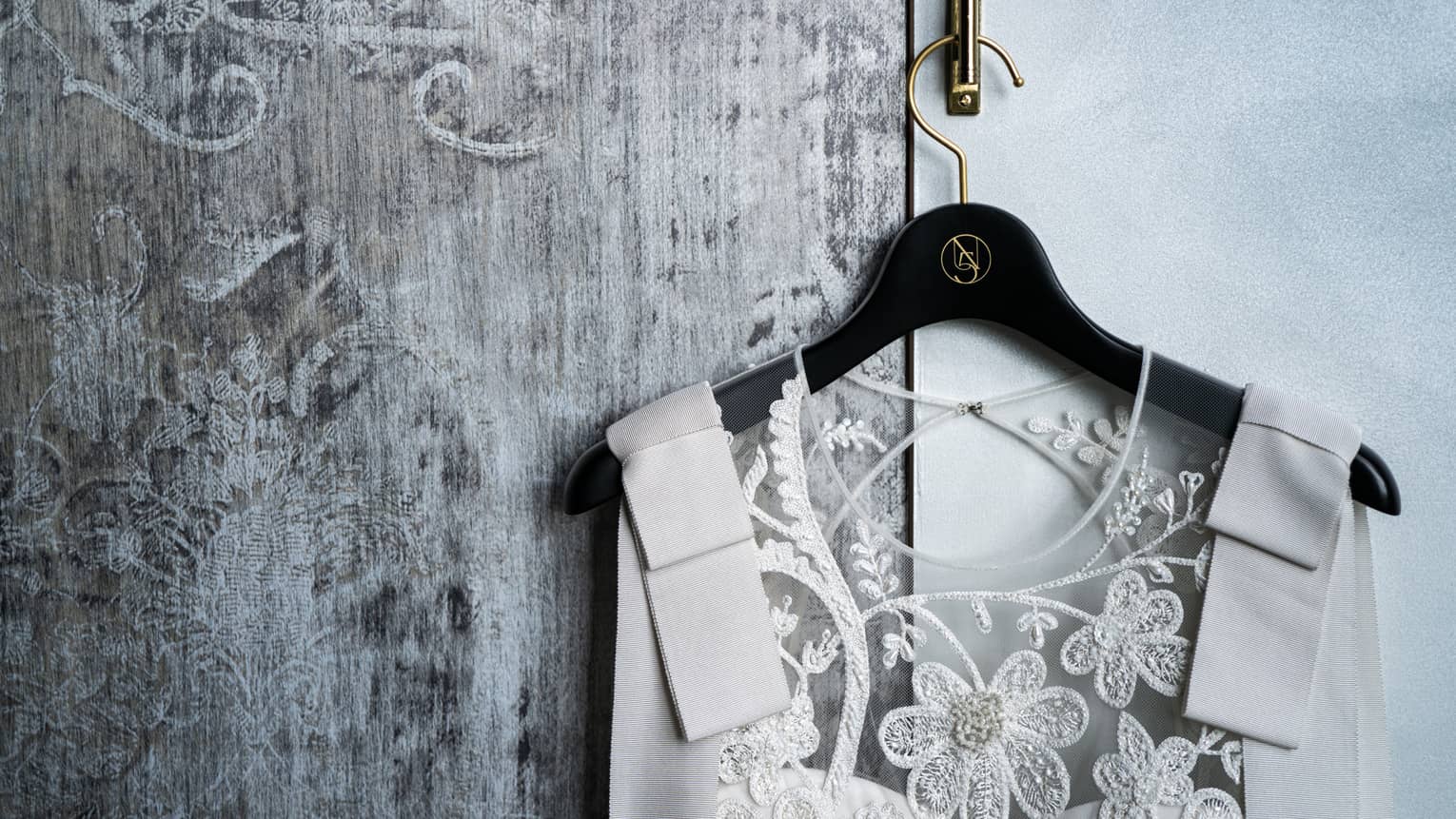 Close-up of wedding dress on hanger with lace flower bodice