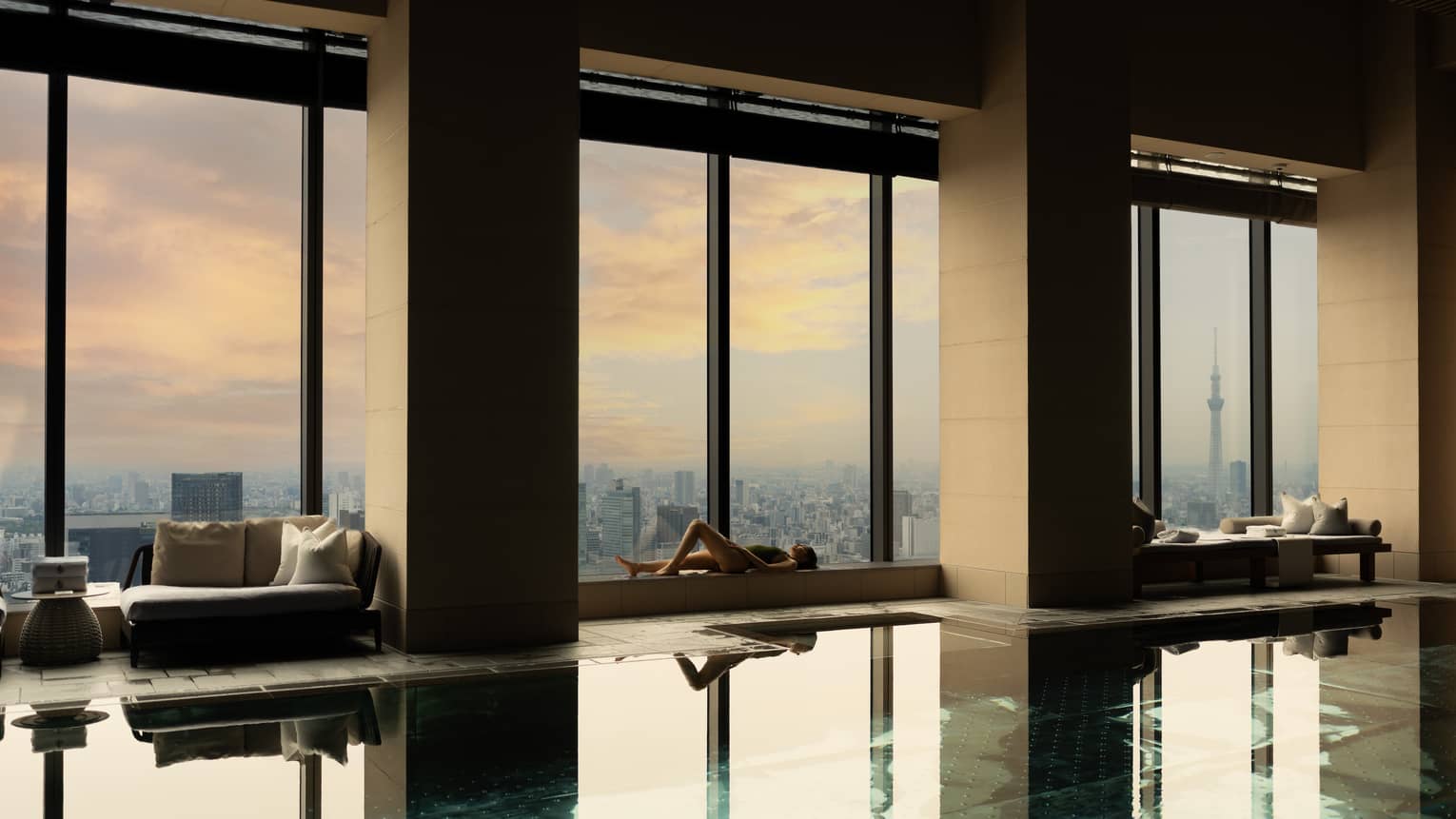 Indoor hotel pool with wall of windows overlooking city