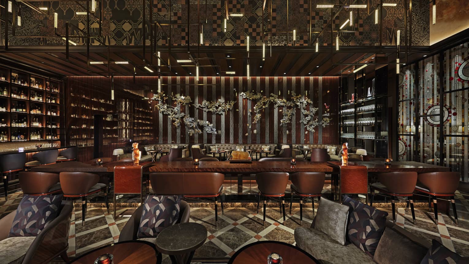 Long rectangular banquet tables with high-backed leather seats, fully-stocked bar wall to the left, lowlighting, wood decor