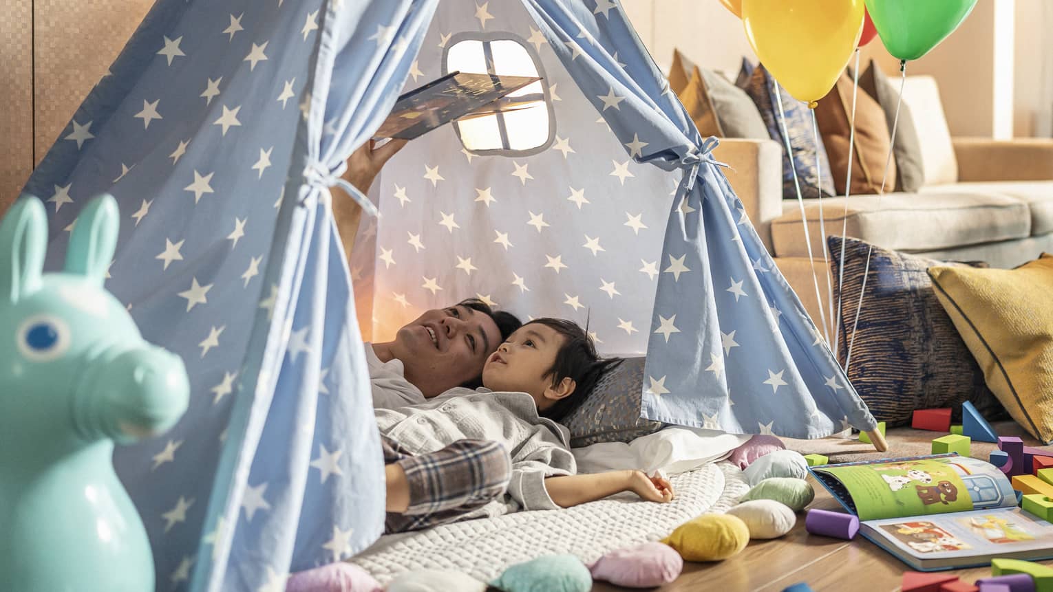 Father reads to young son in their in-room tent