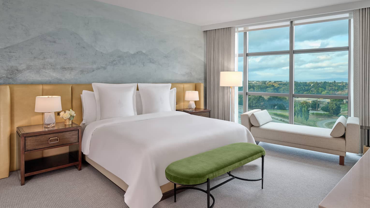 Bedroom with soothing motif on accent wall, king bed, bench and windowside chaise