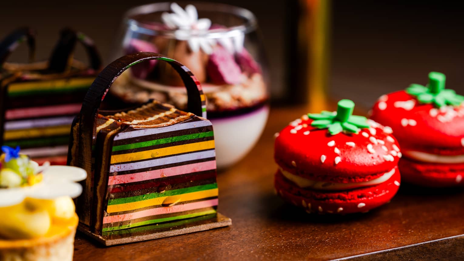 Two strawberry macarons with other desserts on a display