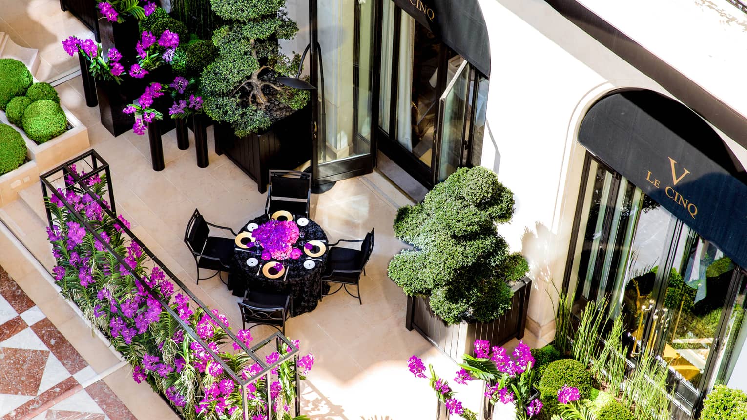 Aerial view of dining table on street-side patio, purple flowers, shrubs