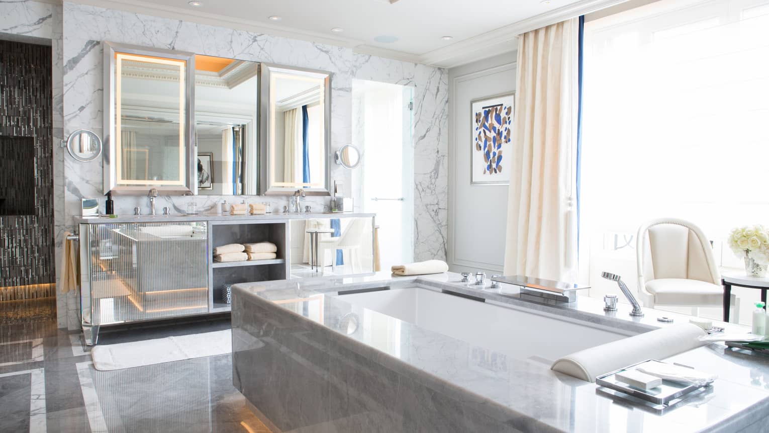 Large luxury bathroom with sunken tub, double vanity, window and marble floors and walls