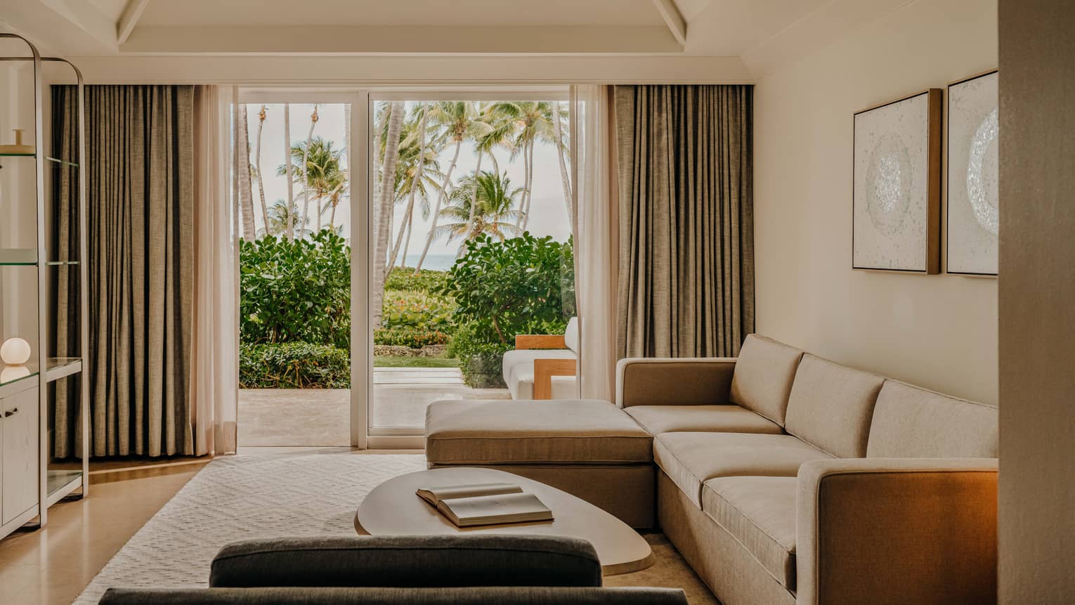 Contemporary living room of a resort suite, featuring a light-brown sofa and walk-out terrace