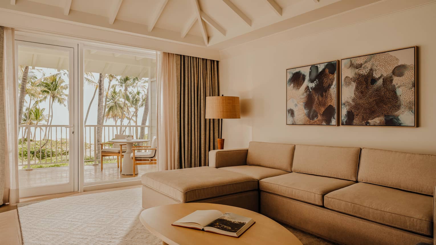 Living room of a resort suite, featuring a light brown sofa and walk-out oceanfront balcony