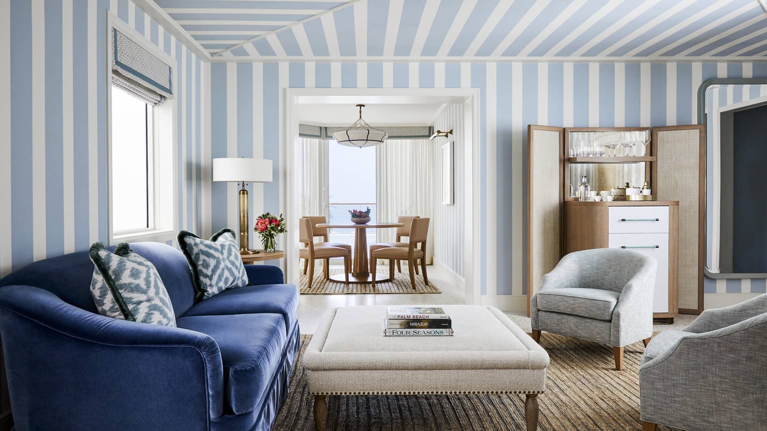 Blue and white striped wallpaper accents a living room with comfortable furniture