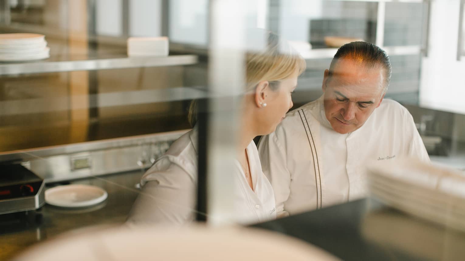 Two chefs talking in a kitchen.