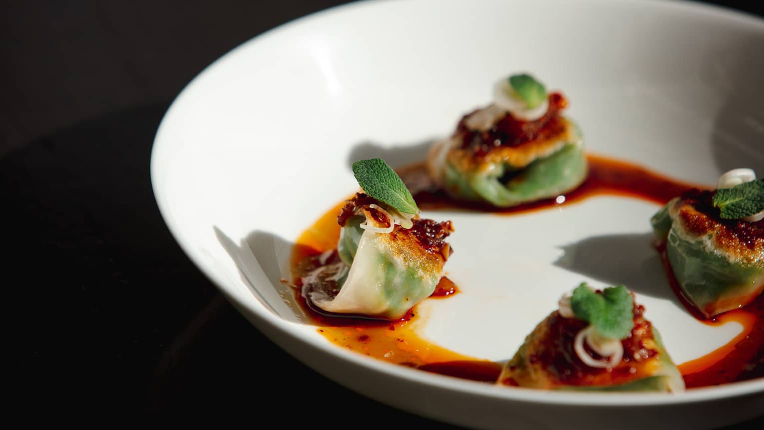 Small foods on a white plate in a red sauce.