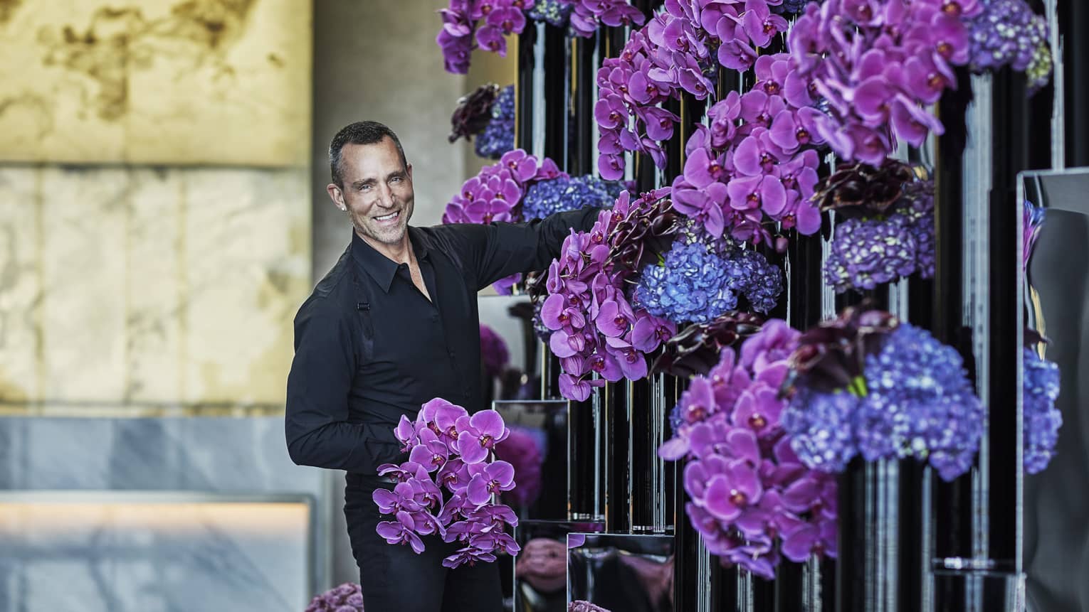 Florist arranges purple and blue flowers in tall black vases