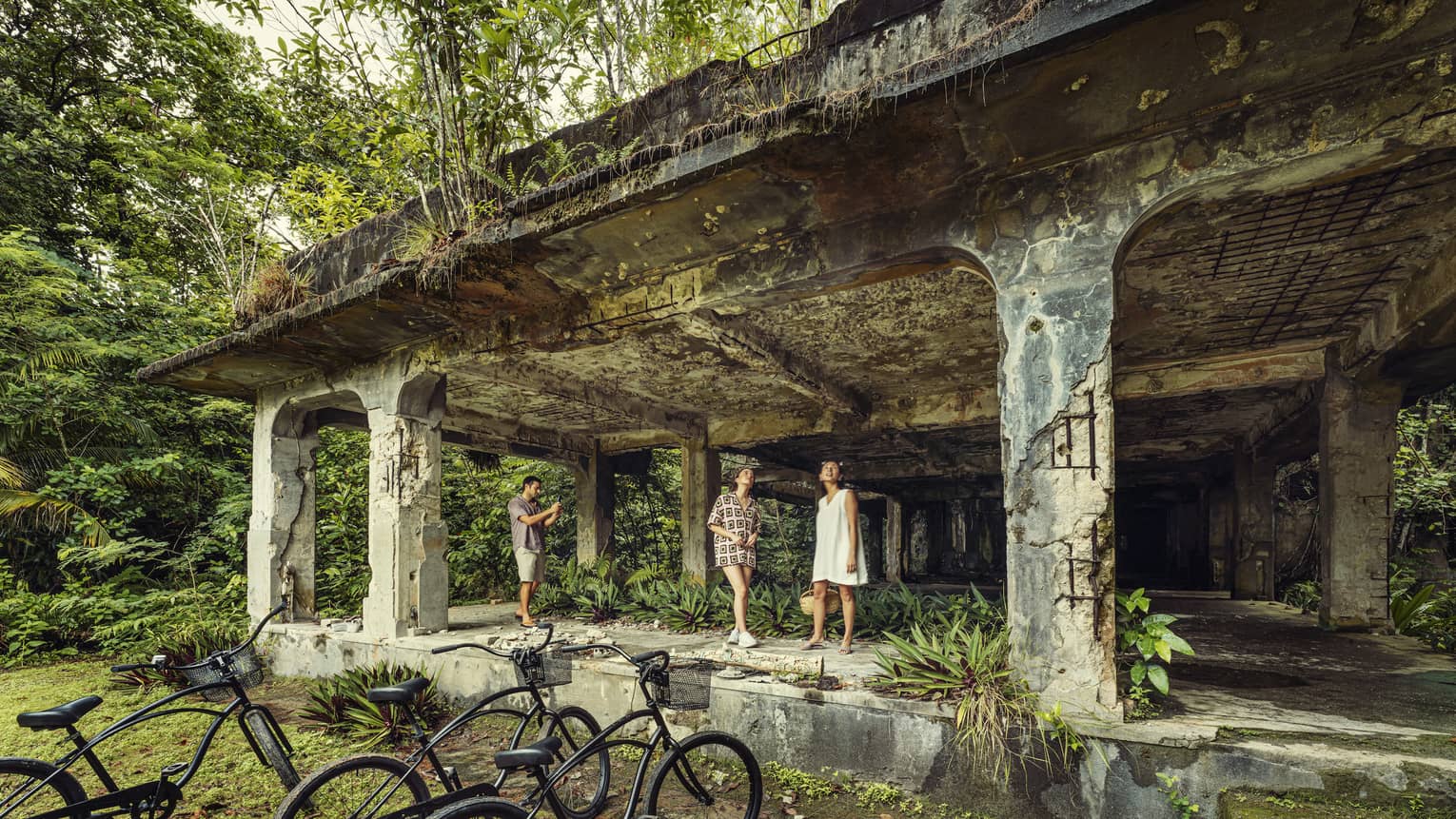 Two women and a man explore the Peleliu Island WWII relics, bicycles in foreground