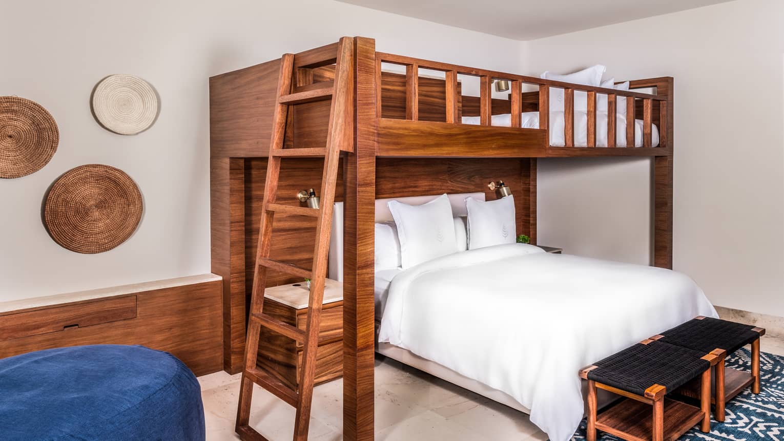 Bedroom with a wooden bunk bed, in which a king bed is positioned perpendicularly to the top queen bed.