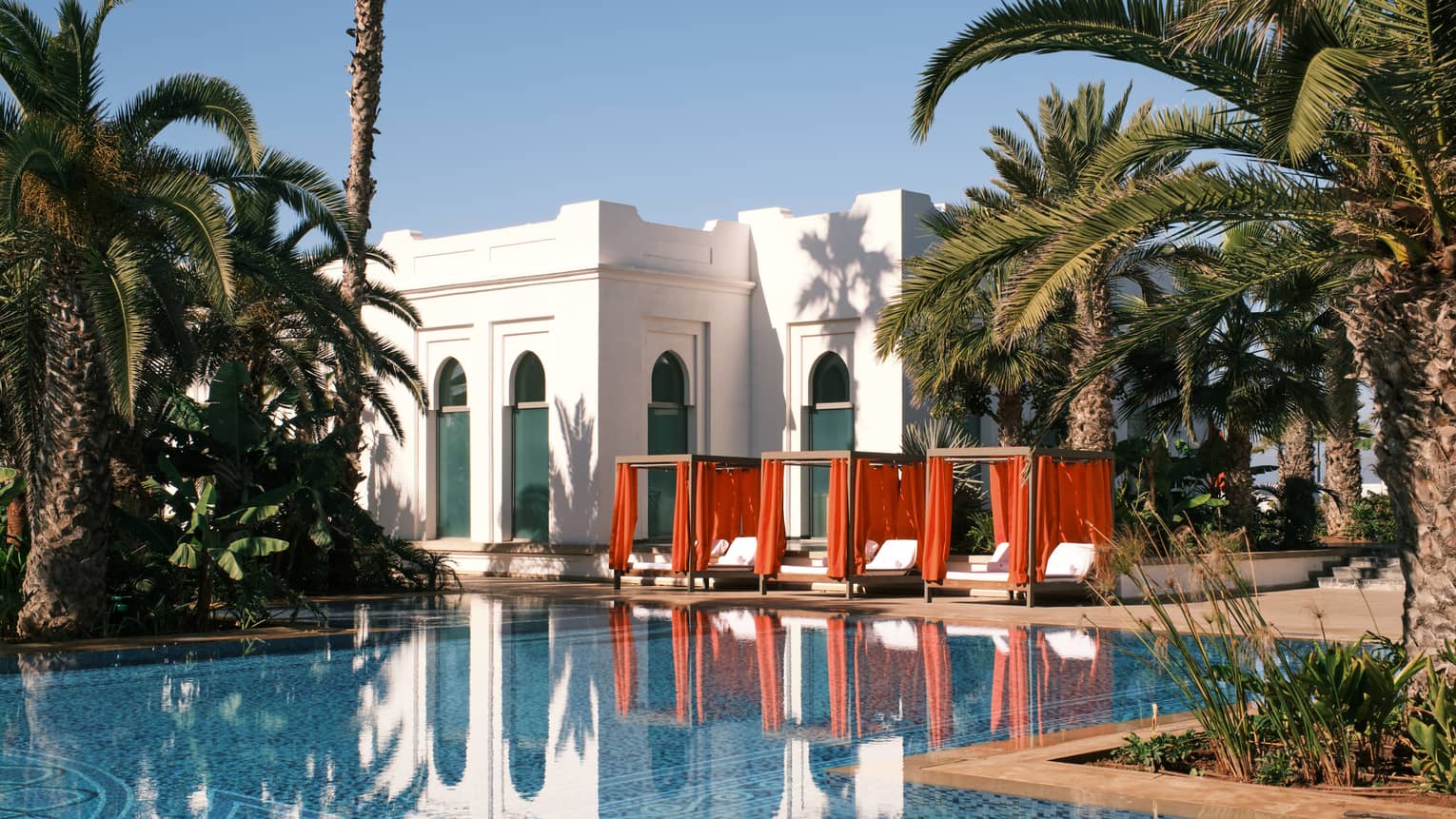 Moroccan luxury resort pool with three red cabanas