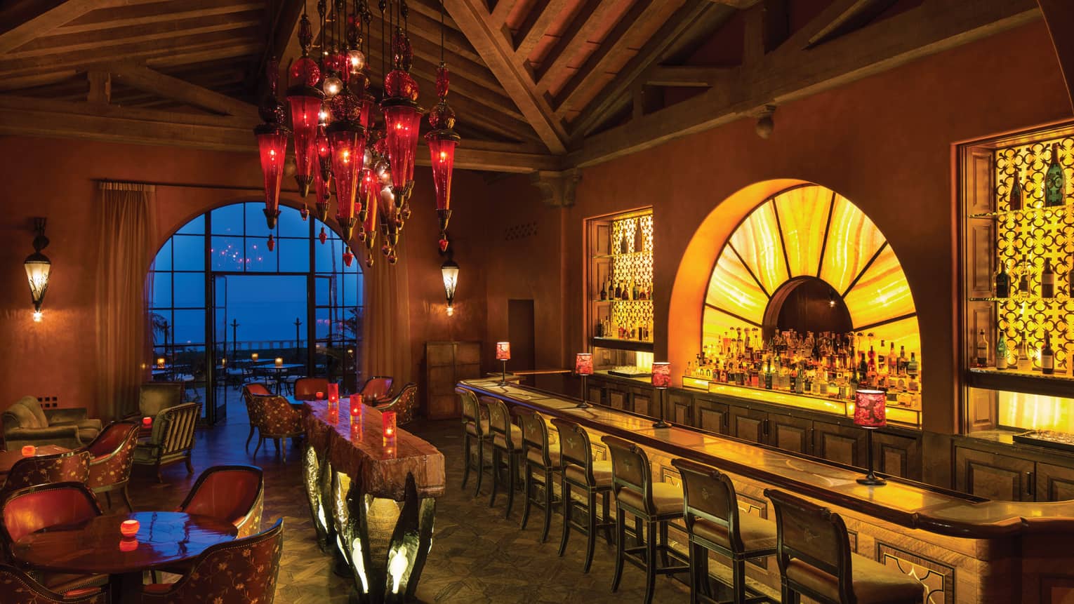 Ty Lounge illuminated arch behind long bar, red lanterns hang over cocktail tables from wood ceiling
