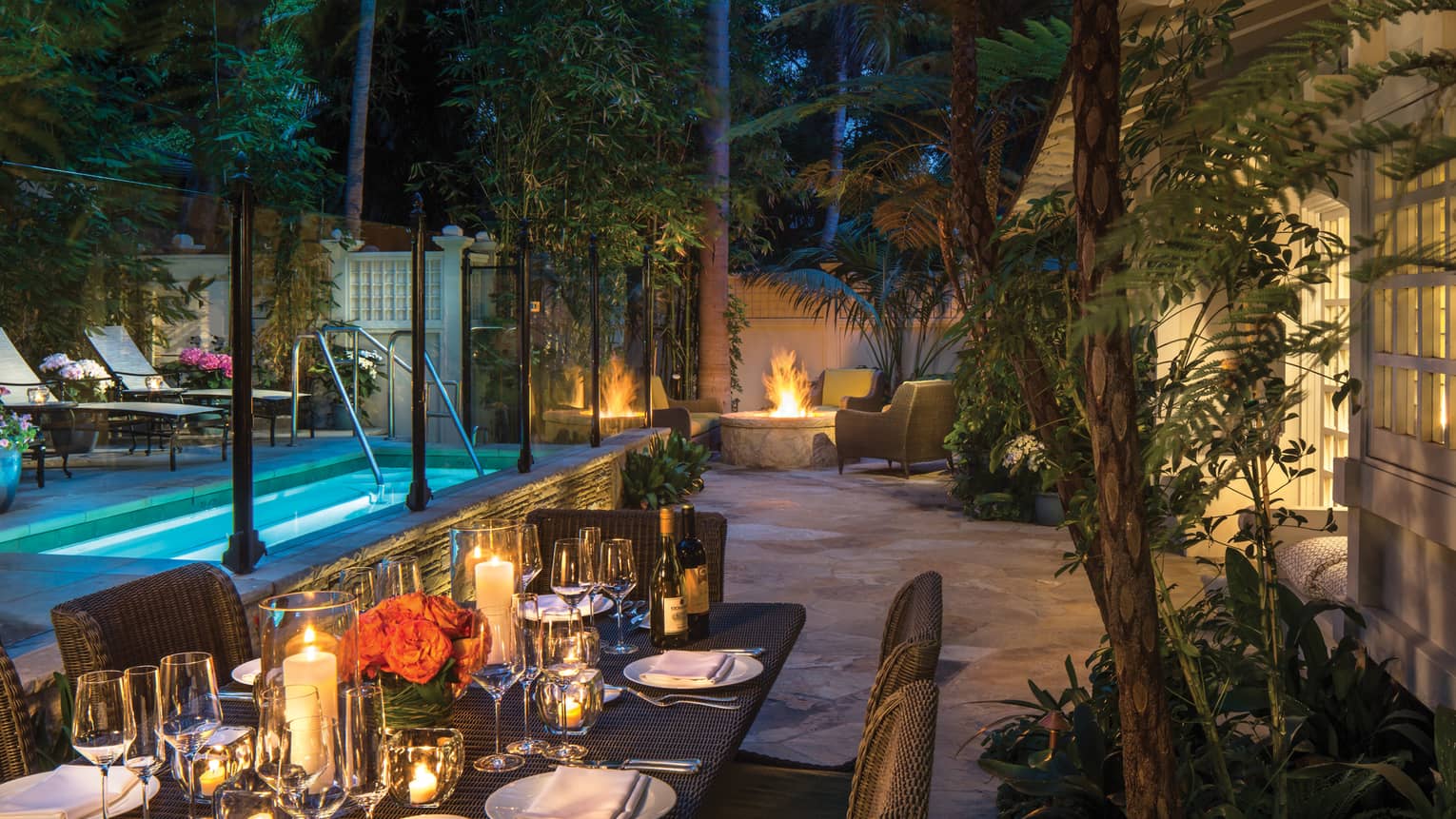 Ty Warner bungalow backyard candle-lit patio dining table by plunge pool, fire pit at night