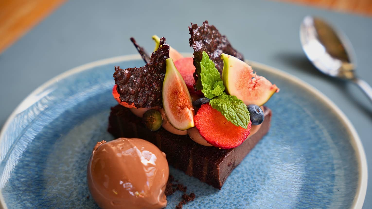Chocolate cake on a blue plate with slices of fruit on top