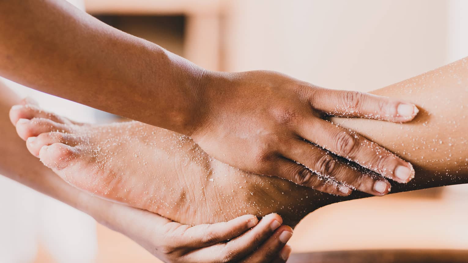Hands hold a person's foot and ankle in a spa