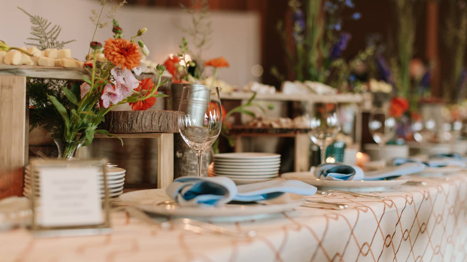 Wedding dining table set with flowers, cheeses on rustic wood platters