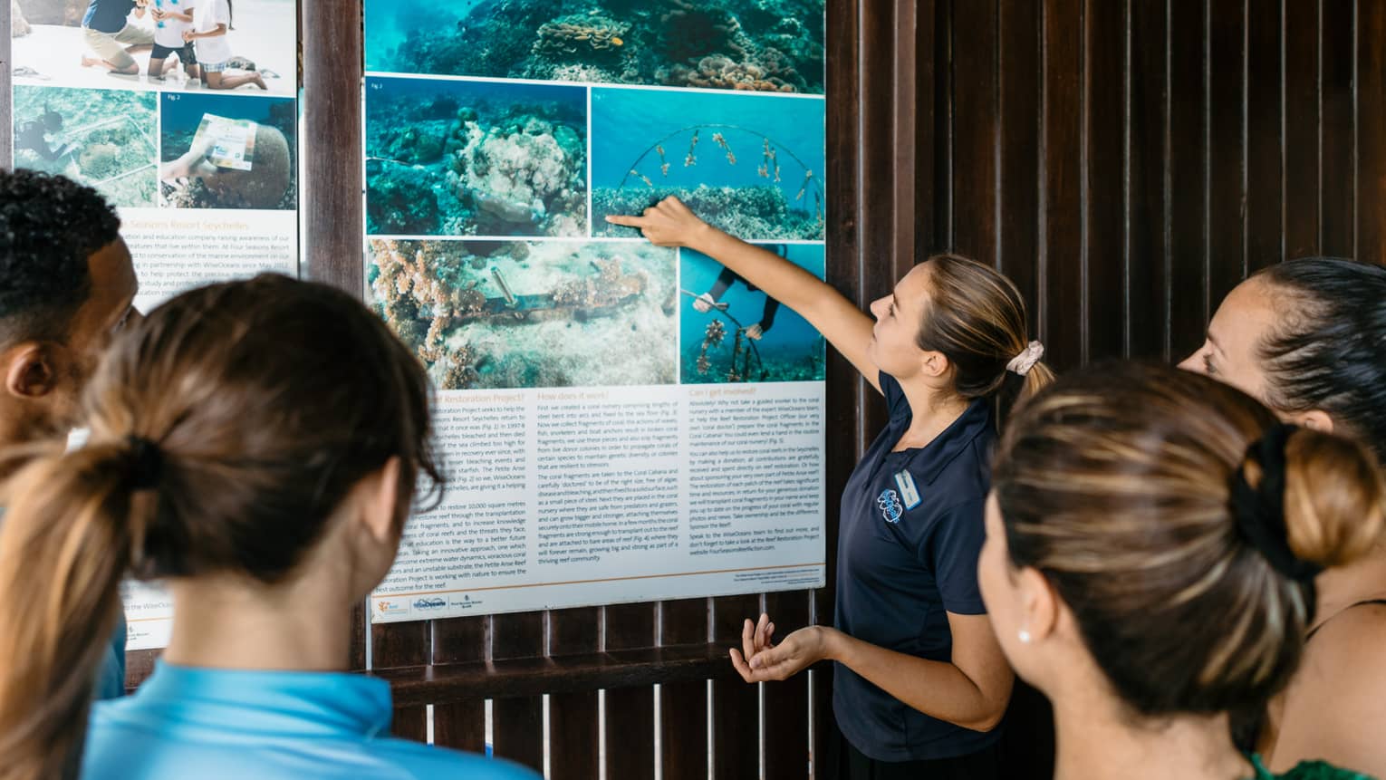 WiseOceans educator pointing at wall poster in front of group