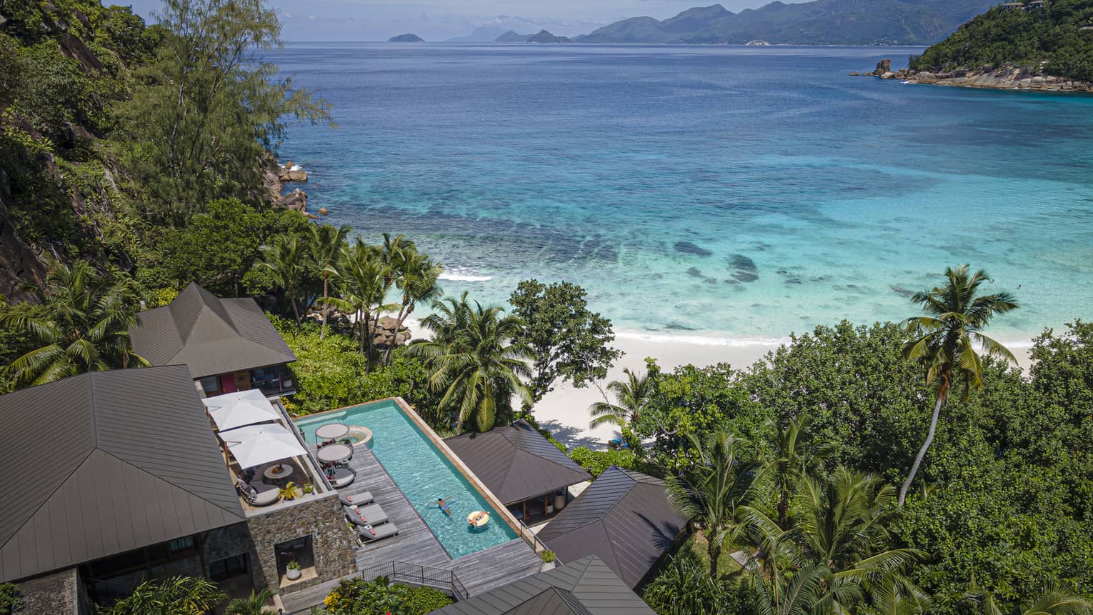 Private villa with private pool nestled among tropical foliage and set on white-sand beach by clear blue ocean