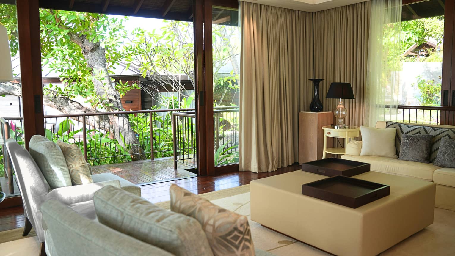 Living room featuring two arm chairs, a sofa, and a large square coffee table, with walk-out garden terrace