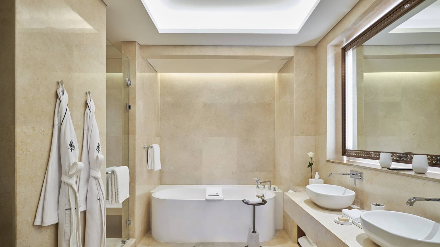 Bathroom with tub, two robes, two sinks, illuminated ceiling lights