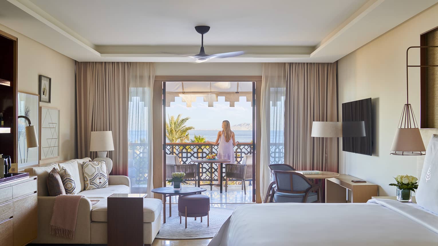 Woman stands on balcony connected to hotel room